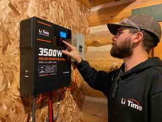 Off grid cabin owner adjusting a LiTime 3500W solar inverter charger inside a North Idaho cabin