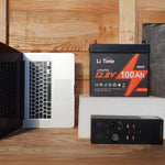 LiTime mini small size lithium battery 12.8V 100Ah next to a laptop and power station