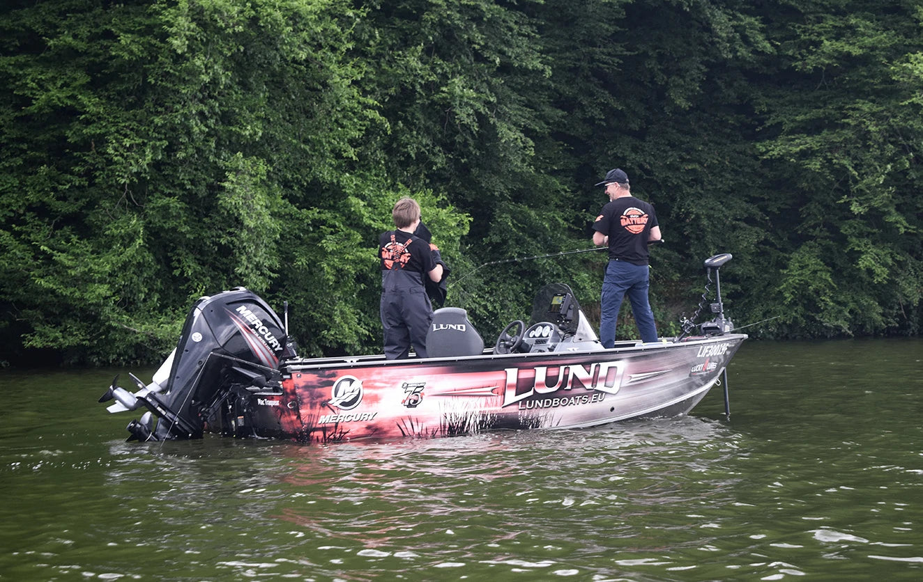 A man and a child wearing litime t-shirt fish together from a Lund professional fishing boat 