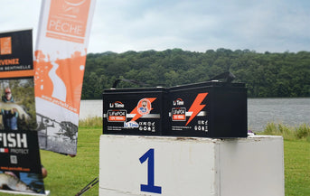 Two LiTime 100Ah batteries sit on the first-place block of a winners' podium at the Peche Fishing Game event