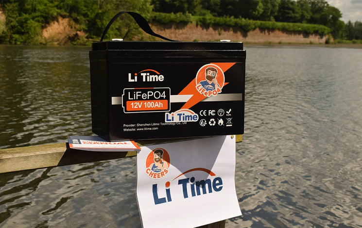 a LiTime 12V 100Ah battery sitting on a wooden dock with a lake in the background