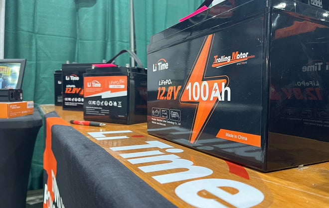 A close-up shot of a LiTime 12.8V 100Ah battery on a branded display table at the JDM Show booth