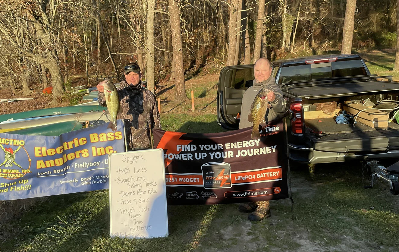 Two anglers pose with their winning bass and litime sponsor banners at the Electric Bass Anglers event