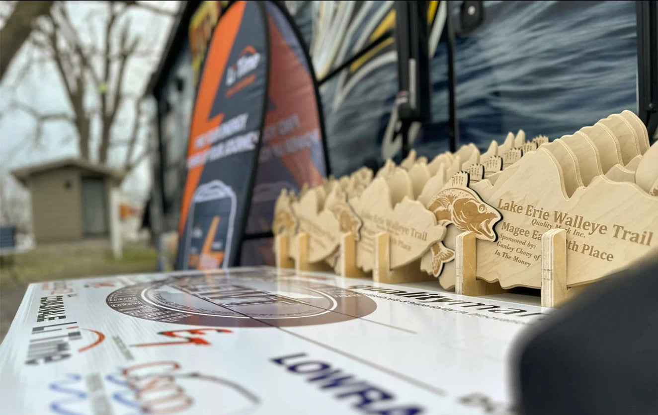 A row of wooden trophies awaits winners of the Lake Erie Walleye Trail, with Li Time sponsor banners in the background