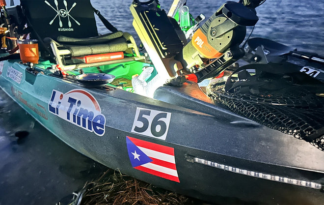 A fishing kayak rigged for night fishing, lit with green and white LEDs and decorated with Li Time and Puerto Rican flag stickers