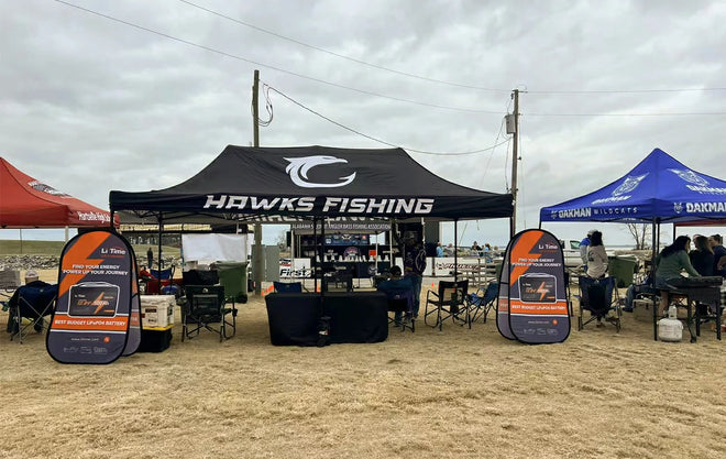 The "Hawks Fishing" team tent, sponsored by Li Time, is set up alongside other teams at an outdoor tournament