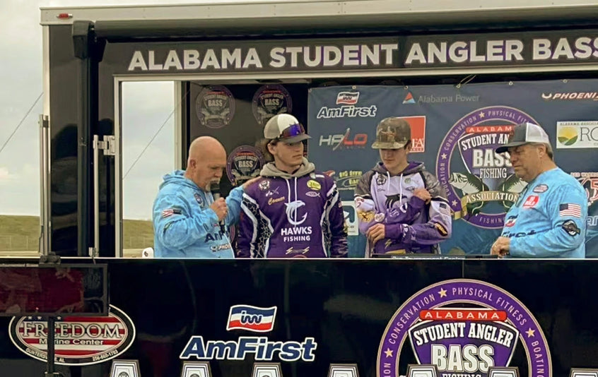 Two student anglers from the "Hawks Fishing" team are interviewed on stage at an Alabama Student Angler tournament