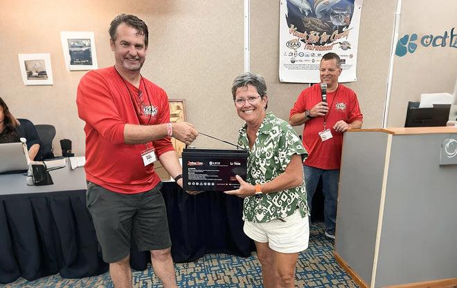 A woman smiles as she is presented with a LiTime battery prize at the Heroes on the Water charity event