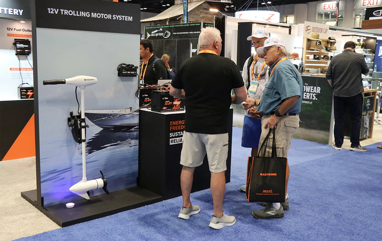 a LiTime staff member explains the 12V trolling motor system to two interested attendees at the ICAST show