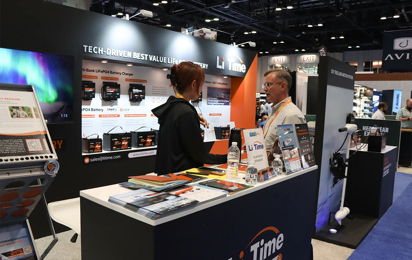 A LiTime staff member speaks with a visitor at the info desk at ICAST
