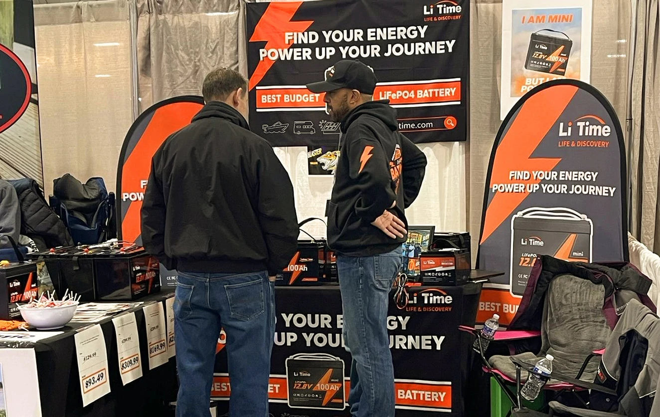 A Li Time representative talks with a customer in their branded booth at an indoor Fishing and Hunting Show