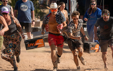 moonlanding RV festival that four people lifting two LiTime 12V 230Ah batteries for a chasing game