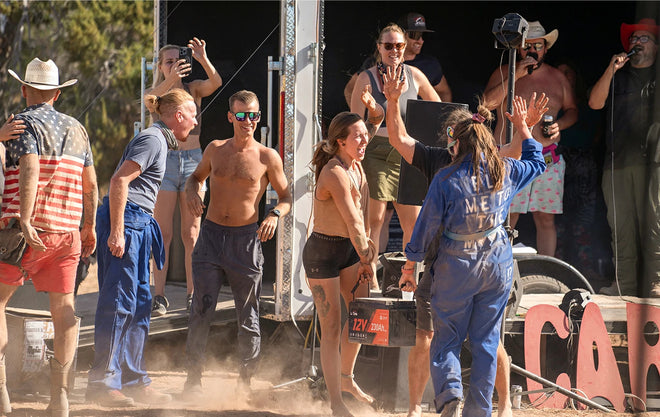A crowd celebrates with the winner of a competition who is holding a large battery prize at the Moonlanding event