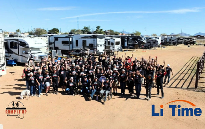 A large group of RVers in matching shirts waves for a photo in front of their rigs at the Romp It Up Music Festival