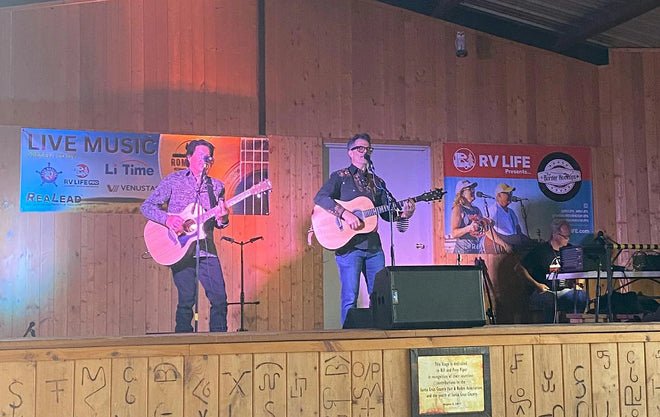 A band performs on stage at the Romp It Up Music Festival, in front of a sponsor banner featuring the LiTime logo