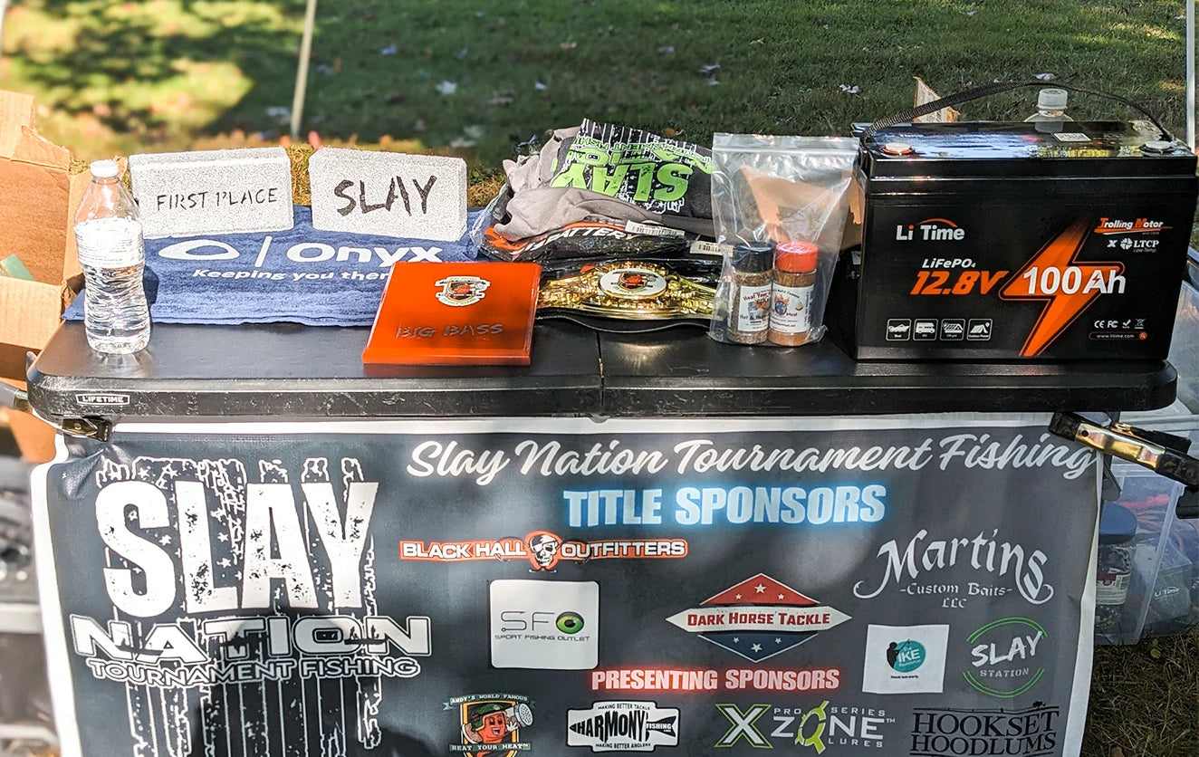 The first-place prize package at a Slay Nation tournament, featuring a LiTime battery, a plaque, and a championship belt