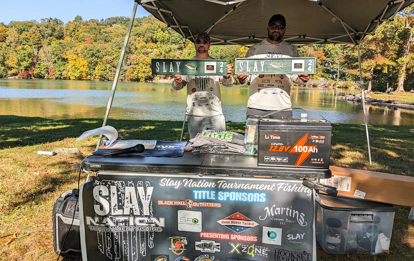A winning Slay Nation team poses with their awards behind a prize display that prominently features a LiTime battery
