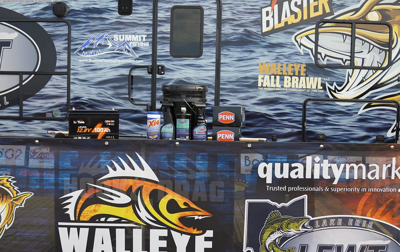 A LiTime battery, PENN reel boxes, and other sponsor products displayed against the Walleye Fall Brawl event wrap