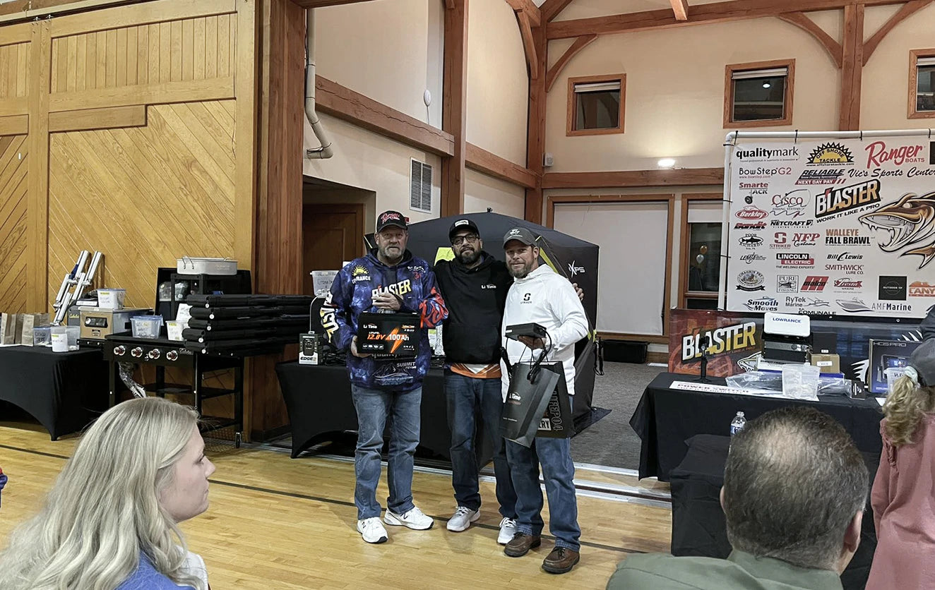A winning team of three fishermen on stage at the Walleye Fall Brawl, holding  LiTime batteries