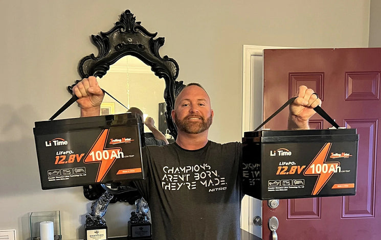 a man of MLF winner holding two of LitIME 12V 100Ah trolling motor batteries