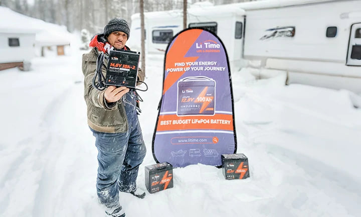 A man braves the snow while holding a LiTime 12V batteries, promoting winter camping energy solutions