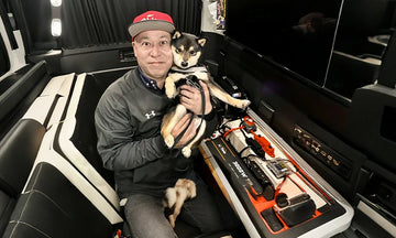 a man holds a dog while showcasing a LiTime lithium battery setup in a van, highlighting space and functionality