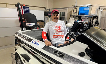 A customer smiles from the seat of a bass boat with litime sticker parked in a garage