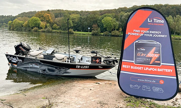 A bass boat beached on a shoreline next to a tall, orange and blue LiTime promotional flag