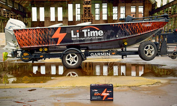 A LiTime branded fishing boat on a trailer with a LiTime battery sitting on the ground in front of it