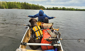 A couple and their dog enjoy a relaxing day of fishing from their canoe on a vast lake with litime trolling motor bettery