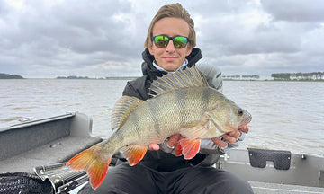 A happy angler proudly shows off a large perch she caught from her fishing boat with litime trolling motor battery