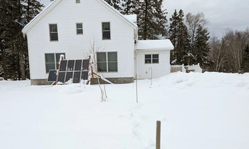 a house in snow day showing litime batteries powering the off-grid living in cold weather